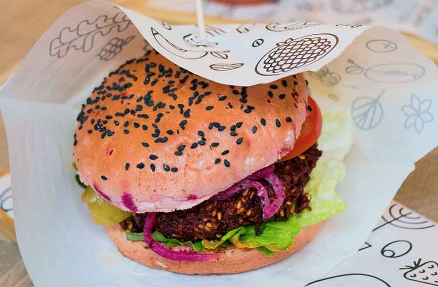 A vegan hamburger sitting on a board wrapped in paper.