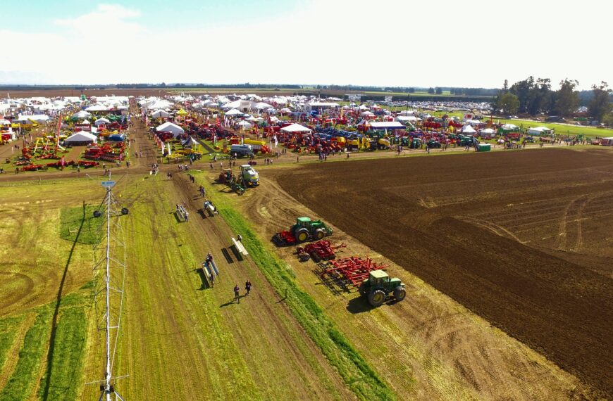Aerial shot of tractors on a large open field at a farming event.
