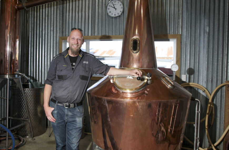 A man stands in a farm-based whiskey distillery.